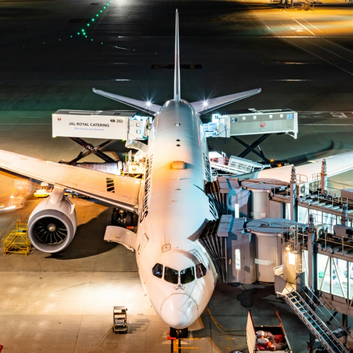 Aerial view of an Airbus being boarded at night in Tokyo's bustling airport.